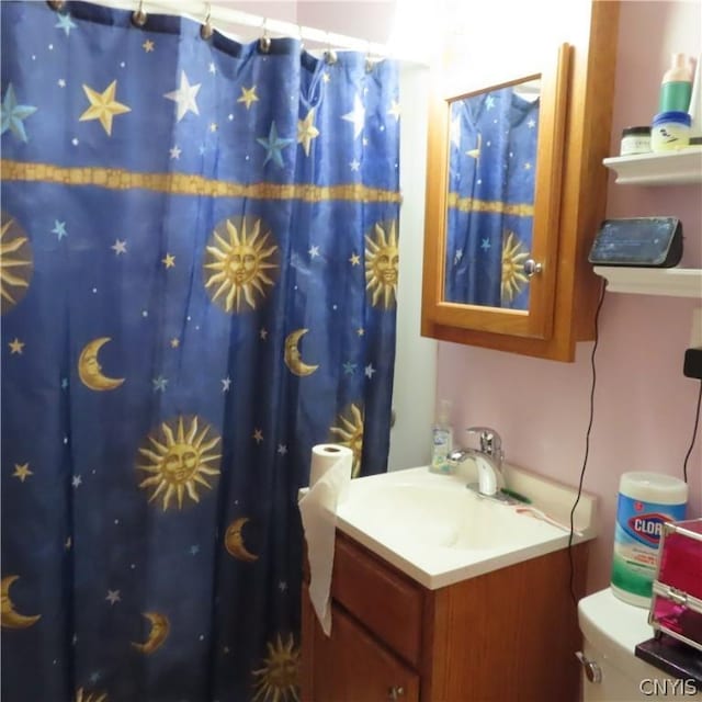 bathroom with curtained shower, vanity, and toilet