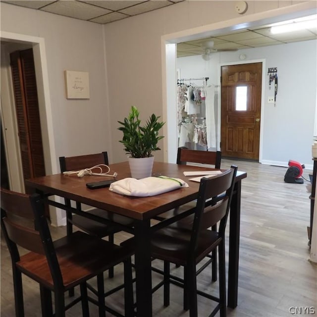 dining area with a drop ceiling and light hardwood / wood-style floors