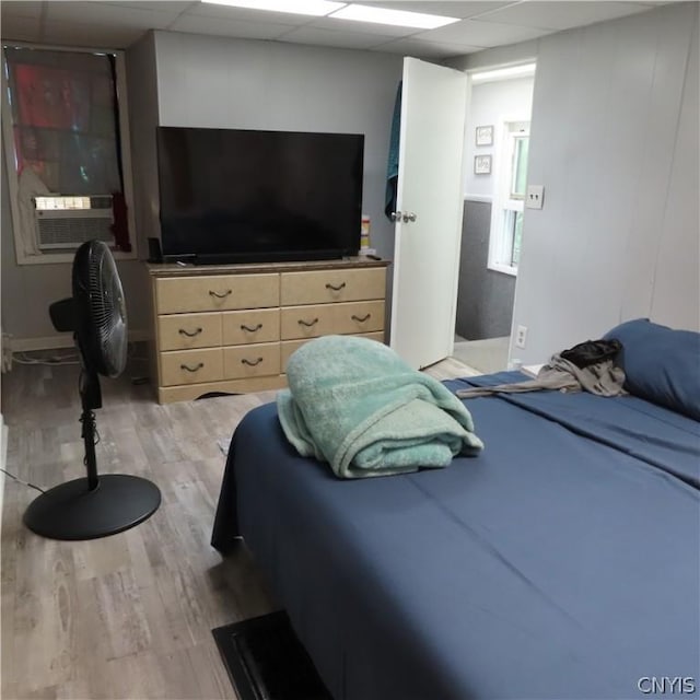 bedroom with a paneled ceiling, light hardwood / wood-style flooring, and cooling unit