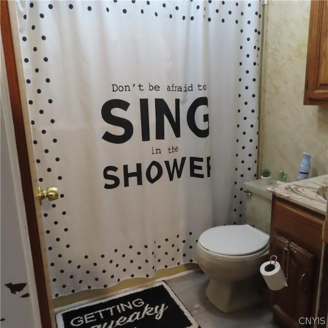 bathroom featuring vanity, toilet, and walk in shower