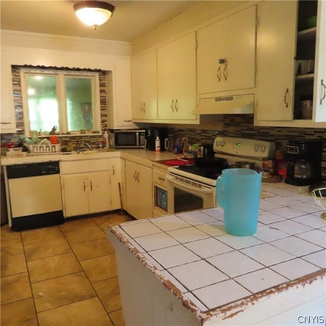 kitchen featuring sink, backsplash, tile countertops, white appliances, and light tile patterned floors