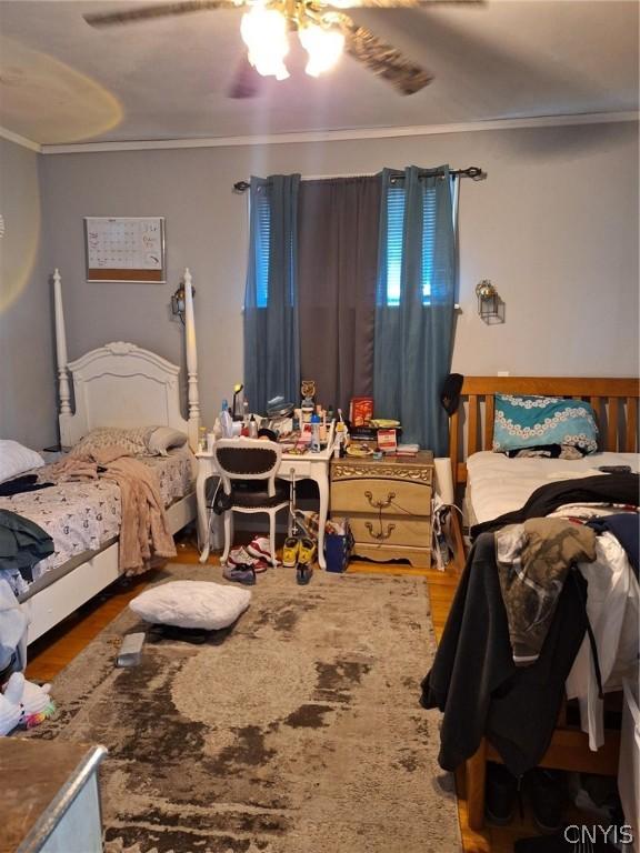 bedroom with ceiling fan, hardwood / wood-style flooring, and ornamental molding