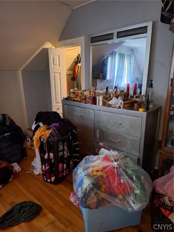 bedroom featuring hardwood / wood-style flooring, a closet, a walk in closet, and vaulted ceiling