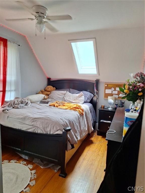 bedroom featuring a skylight, light hardwood / wood-style floors, and ceiling fan