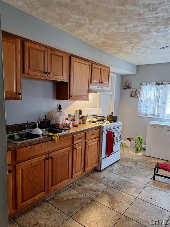 kitchen with white gas stove, sink, fridge, a textured ceiling, and dishwashing machine