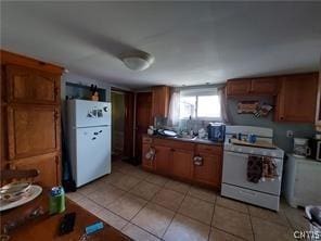 kitchen featuring white appliances, sink, and light tile patterned floors