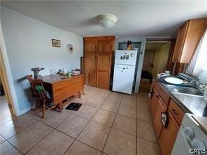 kitchen featuring white fridge, washer / dryer, light tile patterned floors, and sink