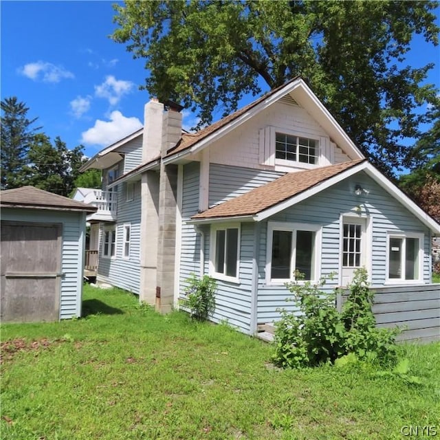 back of house featuring a lawn and a storage shed