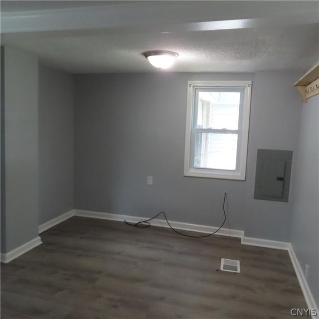 spare room featuring electric panel, dark hardwood / wood-style flooring, and a textured ceiling