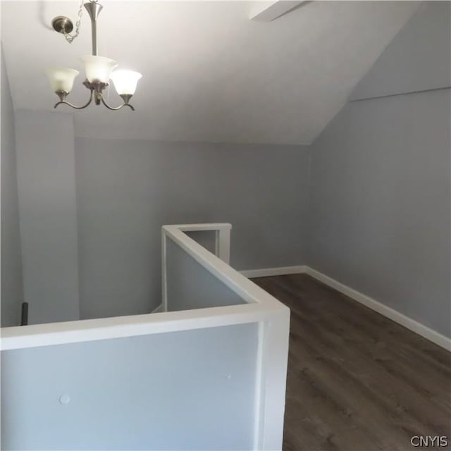 stairs featuring hardwood / wood-style floors, lofted ceiling, and a notable chandelier