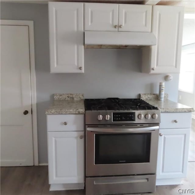 kitchen featuring light stone counters, white cabinets, high end stainless steel range oven, and hardwood / wood-style flooring