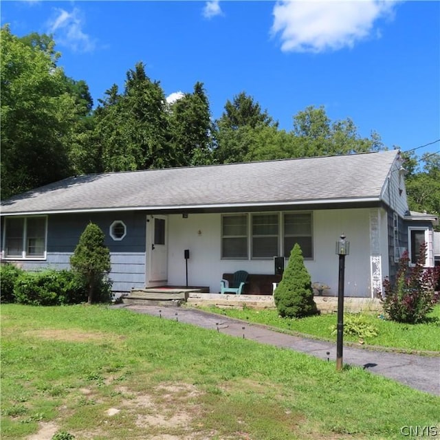 ranch-style house featuring covered porch and a front yard