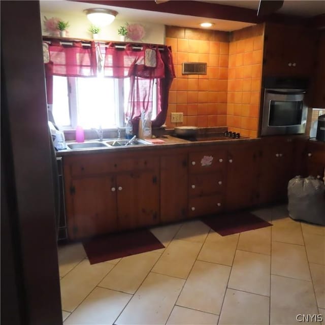 kitchen featuring sink, tile walls, stovetop, oven, and light tile patterned flooring