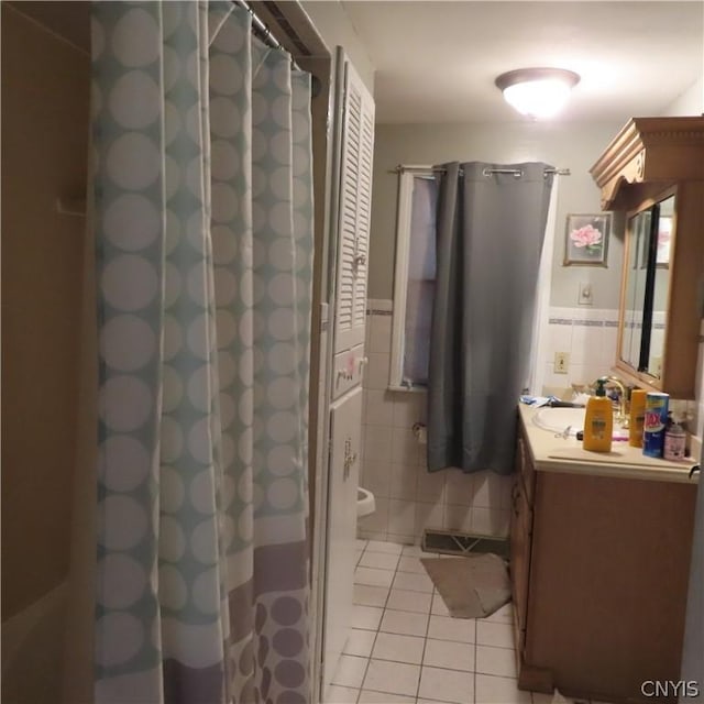 bathroom featuring tile patterned floors, curtained shower, vanity, and tile walls