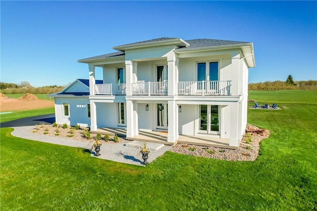 back of house featuring french doors, a balcony, and a lawn