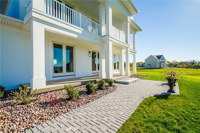 exterior space featuring a lawn, a balcony, and french doors