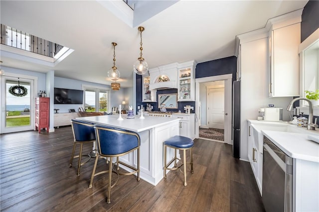 kitchen with a kitchen breakfast bar, stainless steel appliances, pendant lighting, white cabinets, and a kitchen island