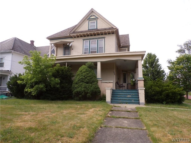 victorian home featuring a porch, a front yard, and brick siding