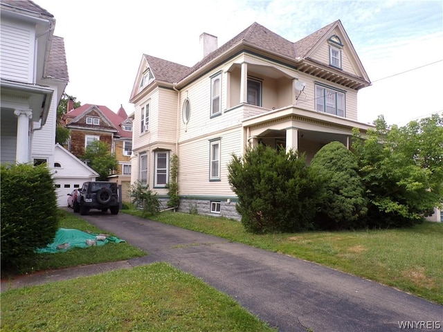 view of side of home featuring driveway, roof with shingles, a yard, and a chimney