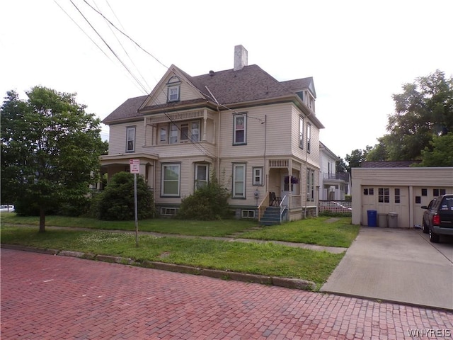 view of front facade featuring a chimney, an outdoor structure, decorative driveway, and a front yard