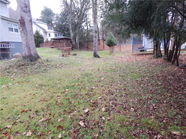 view of yard with a trampoline and a deck