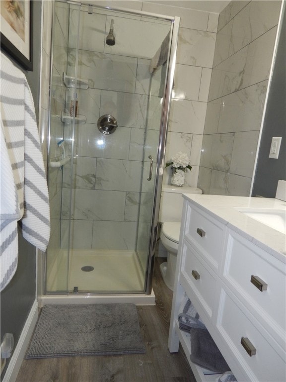 bathroom with a shower with door, hardwood / wood-style flooring, toilet, and vanity