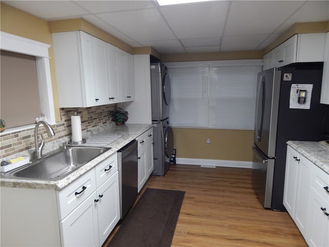 kitchen with a paneled ceiling, sink, light wood-type flooring, and appliances with stainless steel finishes