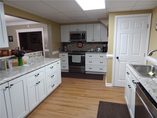 kitchen with a paneled ceiling, light hardwood / wood-style flooring, stainless steel appliances, sink, and tasteful backsplash