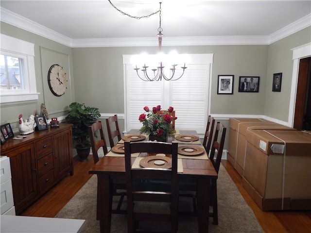 dining area featuring crown molding, dark hardwood / wood-style floors, and an inviting chandelier