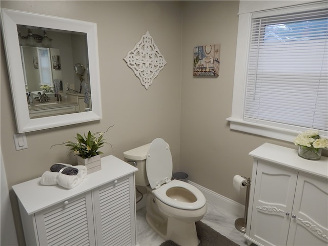 bathroom with tile flooring, vanity with extensive cabinet space, and toilet