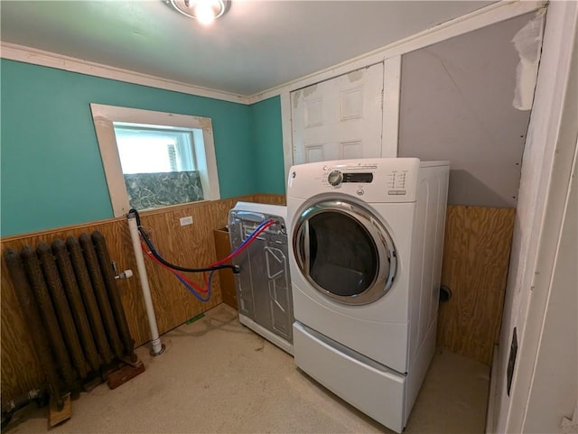 washroom with wood walls, washer / clothes dryer, and radiator