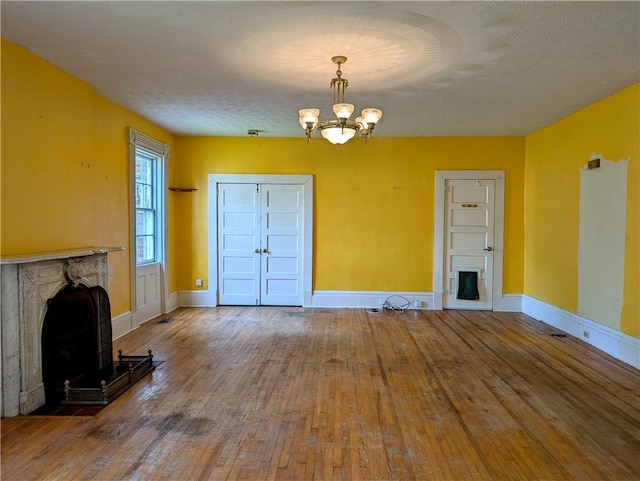 unfurnished living room featuring hardwood / wood-style floors, a textured ceiling, and a chandelier