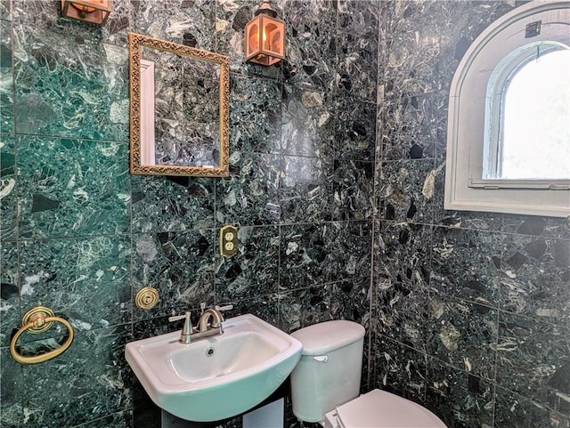 bathroom featuring sink, tile walls, and toilet