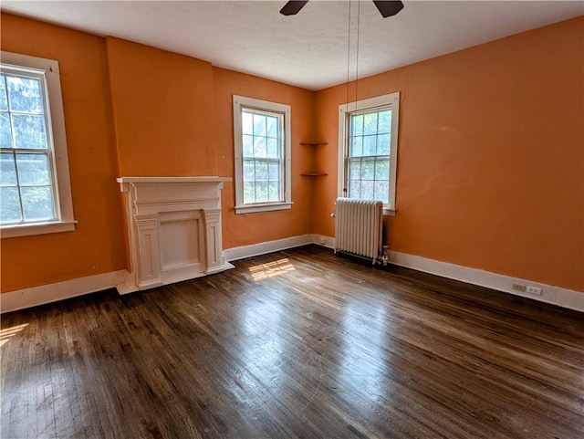 unfurnished living room with radiator heating unit, dark hardwood / wood-style floors, and ceiling fan