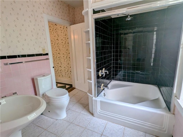 bathroom featuring tile patterned floors, toilet, tiled shower / bath, and tile walls