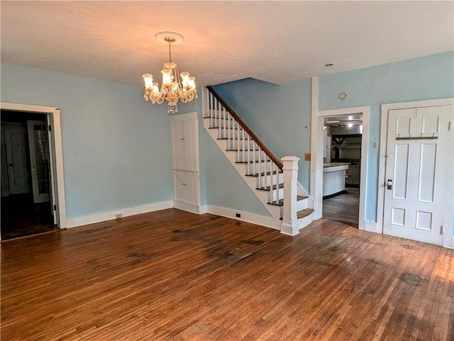 spare room with dark hardwood / wood-style flooring and a notable chandelier