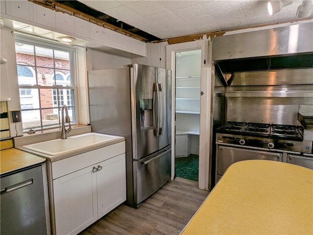 kitchen with light hardwood / wood-style flooring, stainless steel appliances, white cabinetry, and sink