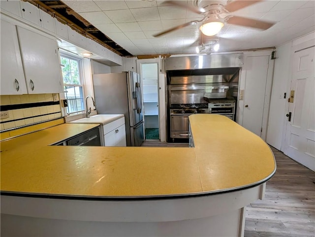 kitchen with ceiling fan, sink, stainless steel appliances, hardwood / wood-style floors, and white cabinets