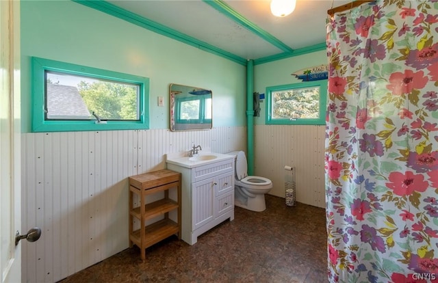 bathroom featuring wood walls, crown molding, vanity, and toilet