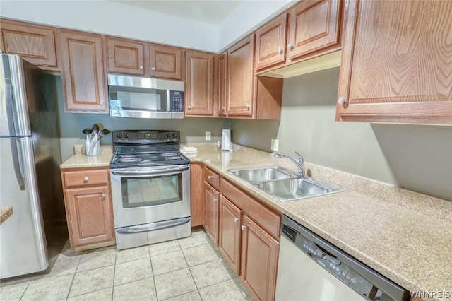 kitchen with appliances with stainless steel finishes, sink, and light tile patterned floors