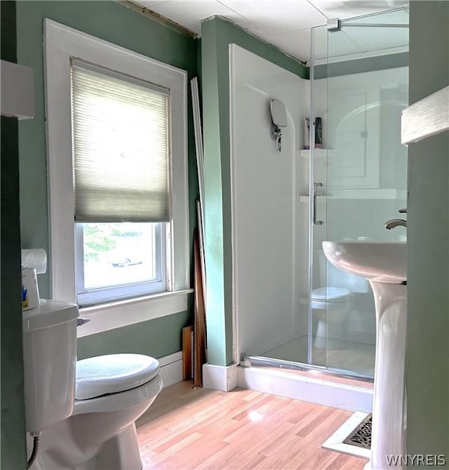 bathroom with plenty of natural light, hardwood / wood-style floors, an enclosed shower, and toilet