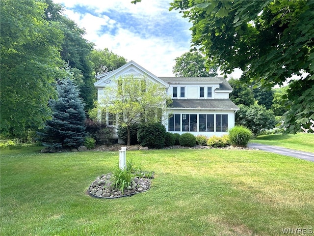 view of front of home with a sunroom and a front yard