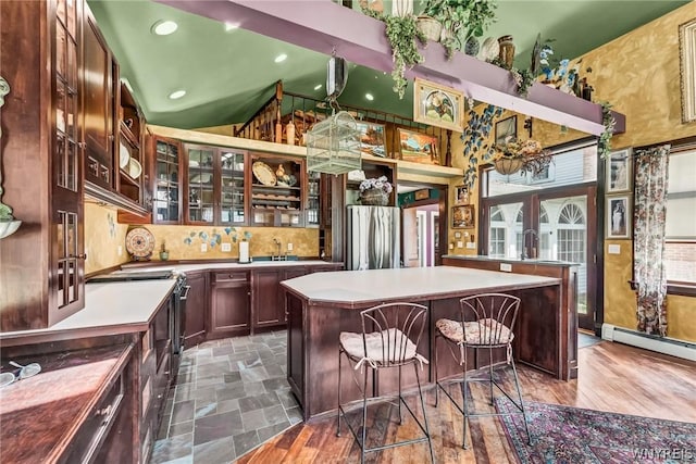 kitchen with lofted ceiling, stainless steel refrigerator, a baseboard heating unit, tasteful backsplash, and a kitchen island