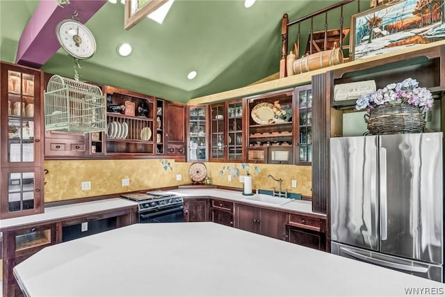 kitchen featuring sink, tasteful backsplash, vaulted ceiling, stainless steel fridge, and gas range oven