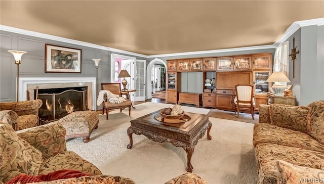 carpeted living room with ornamental molding and a high end fireplace