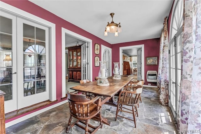 dining area featuring a healthy amount of sunlight, heating unit, a notable chandelier, and french doors