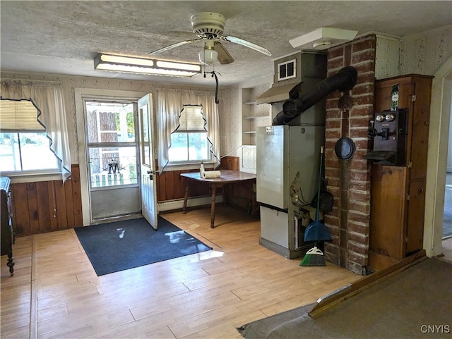 workout area with light wood-type flooring, baseboard heating, and ceiling fan