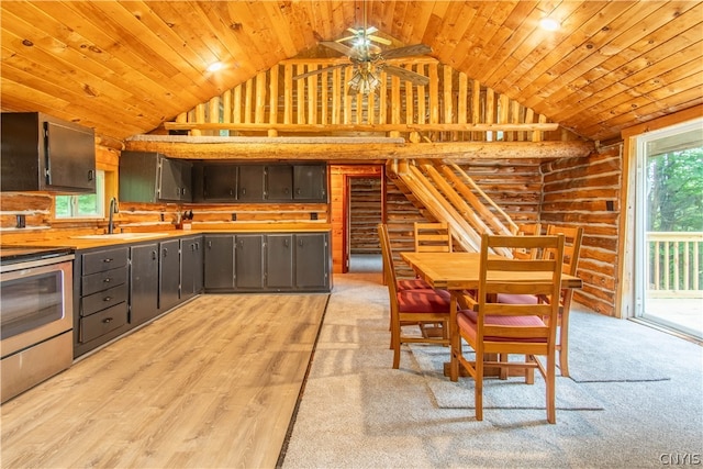 interior space with vaulted ceiling, sink, rustic walls, light wood-type flooring, and ceiling fan