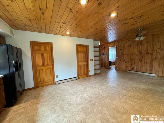 unfurnished living room with a baseboard heating unit, wooden walls, and wooden ceiling