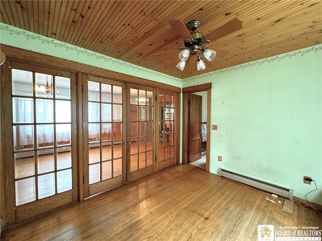 unfurnished room with a baseboard heating unit, wood ceiling, wood-type flooring, and ceiling fan